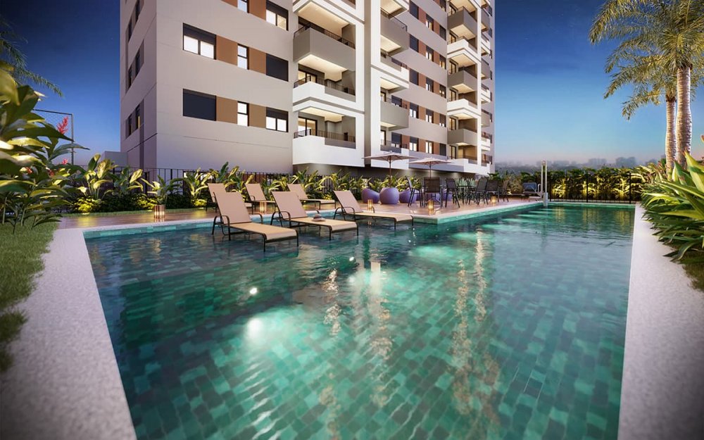 Piscina iluminada à noite com espreguiçadeiras e torre ao fundo