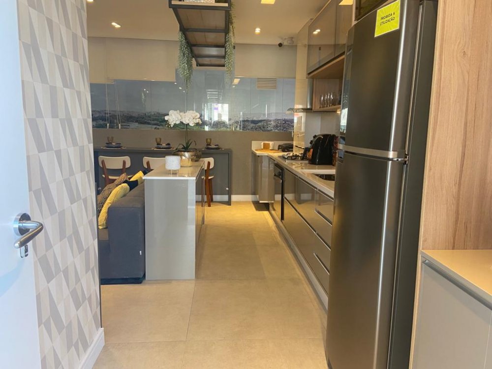 Cozinha com bancada, armários e geladeira integrada ao living