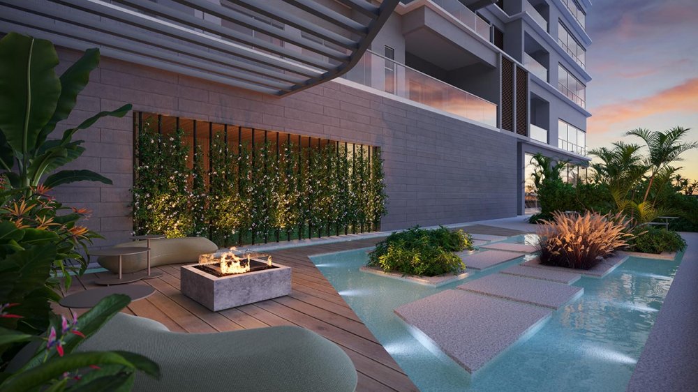 Lounge externo com lareira, deck e espelho d'água ao entardecer